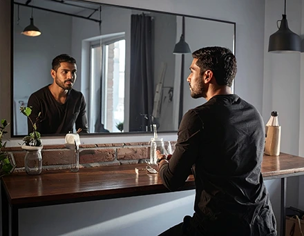 Person sitting at a table looking into a mirror.